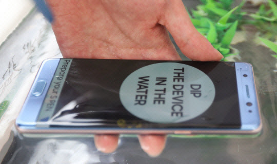 지난 5일 서울 강남구 삼성동 코엑스에 마련된 삼성 갤럭시노트7 체험부스에서 한 시민이 제품의 방수기능을 테스트하고 있는 모습. 사진=연합뉴스